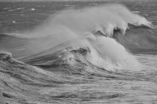 Black and white photo of large waves crashing on the beach