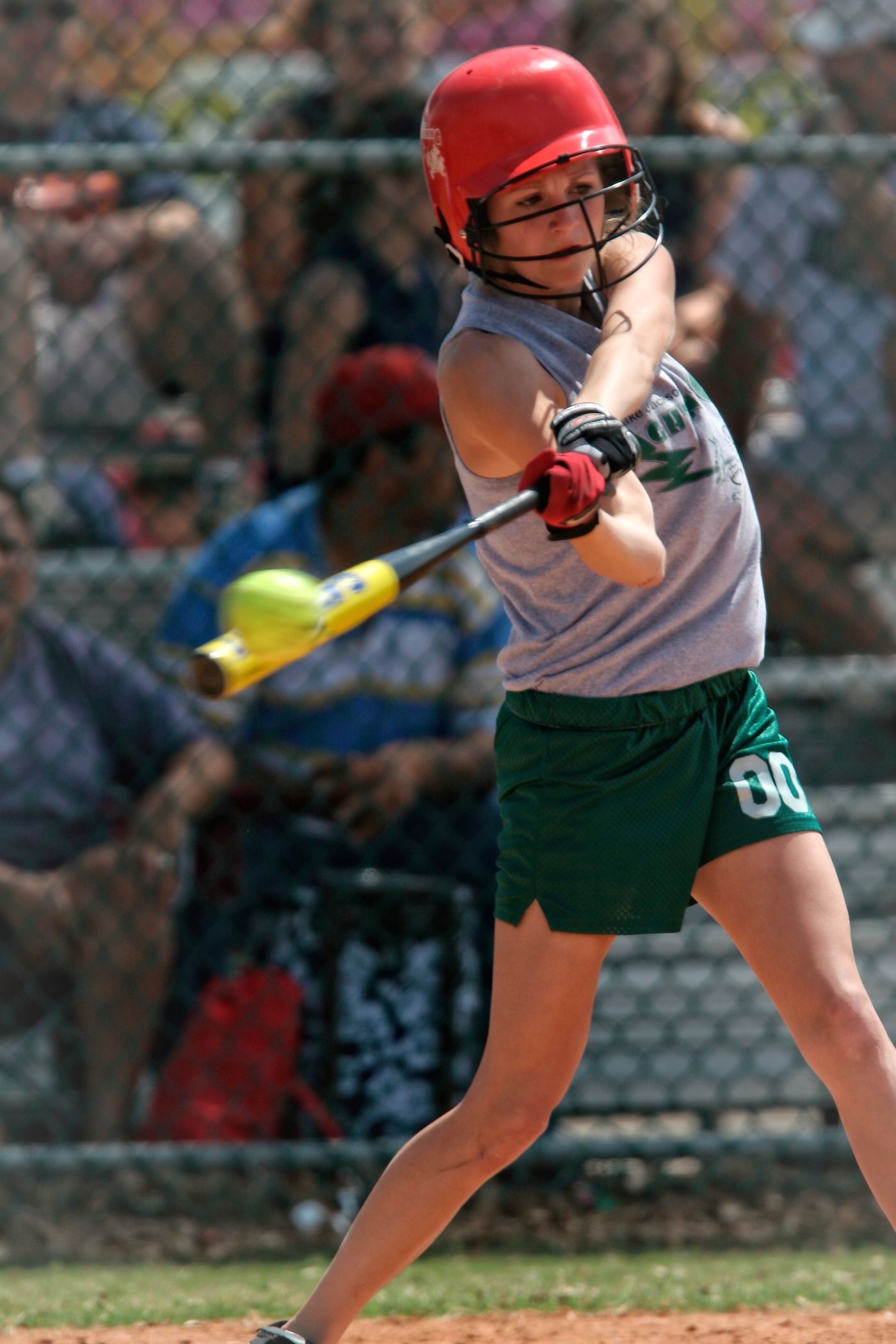 Young batter in a red helmet swinging a yellow bat