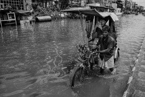 Free A rickshaw navigates a flooded street in Kolkata, showcasing urban resilience. Stock Photo