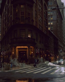Moody street view capturing pedestrians and historic architecture on a misty city crosswalk.