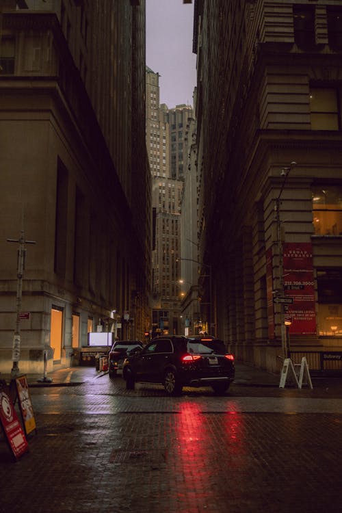 A car is parked in the rain on a city street