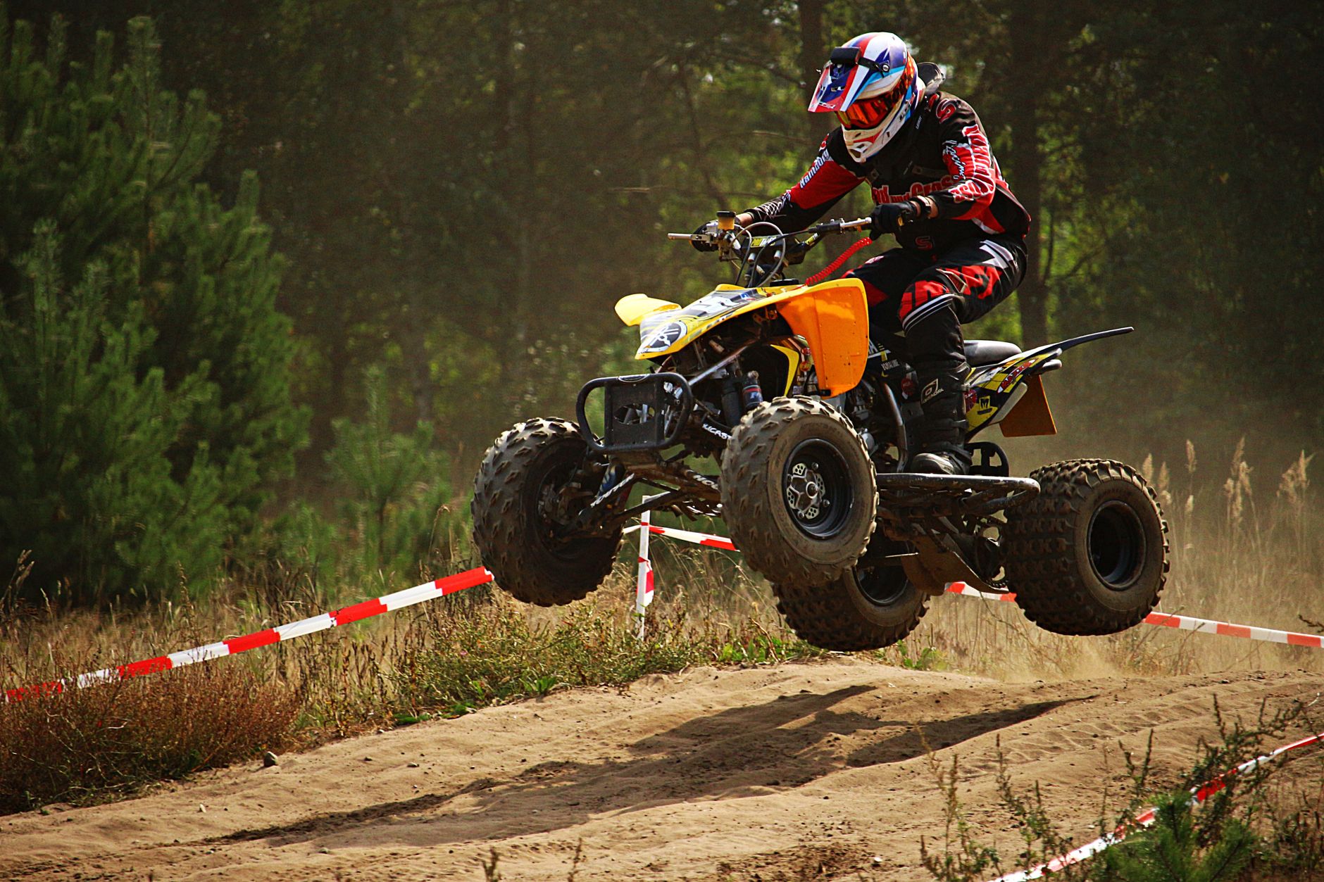 Off-road rider in full safety gear including helmet, goggles, and gloves on a dusty trail