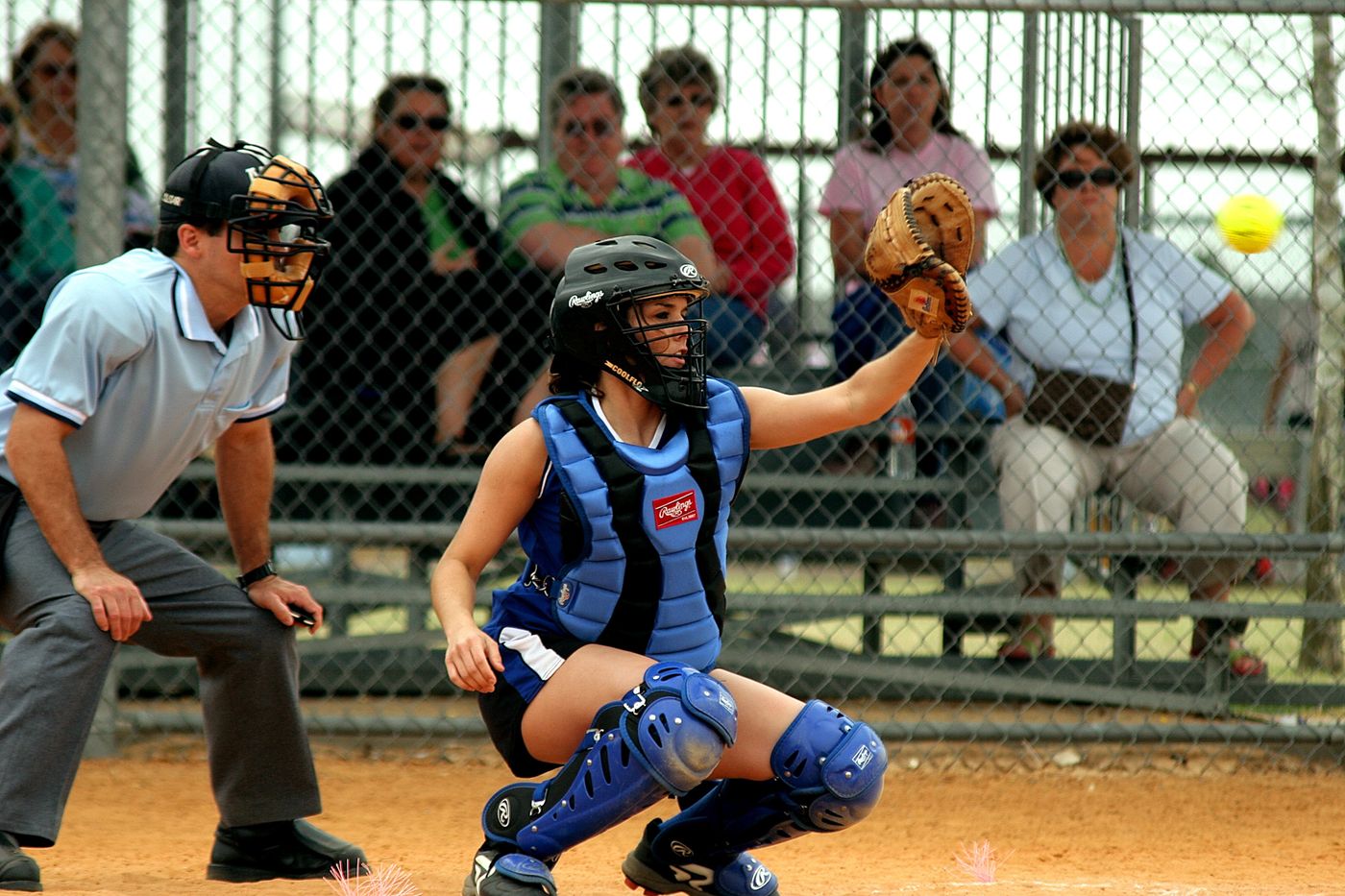 Female catcher catching a pitch as the umpire watches