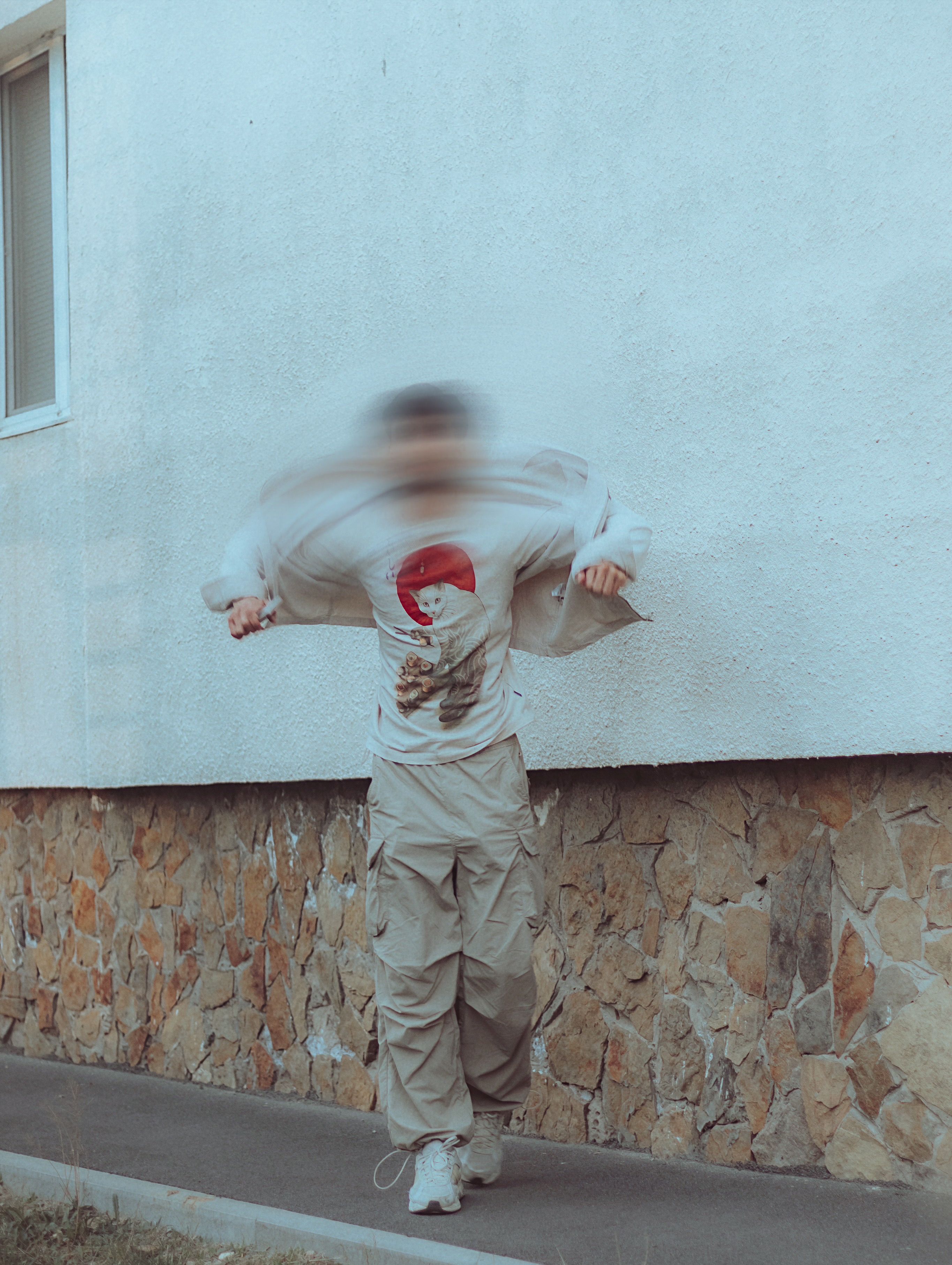 Artistic photograph of a person in motion against a white wall, creating a blurred effect.