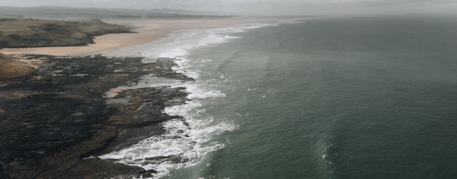 Scenic aerial view of the Northumberland coastline with rocky seacoast and waves.