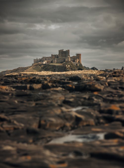 A castle sits on a rocky shore under a cloudy sky