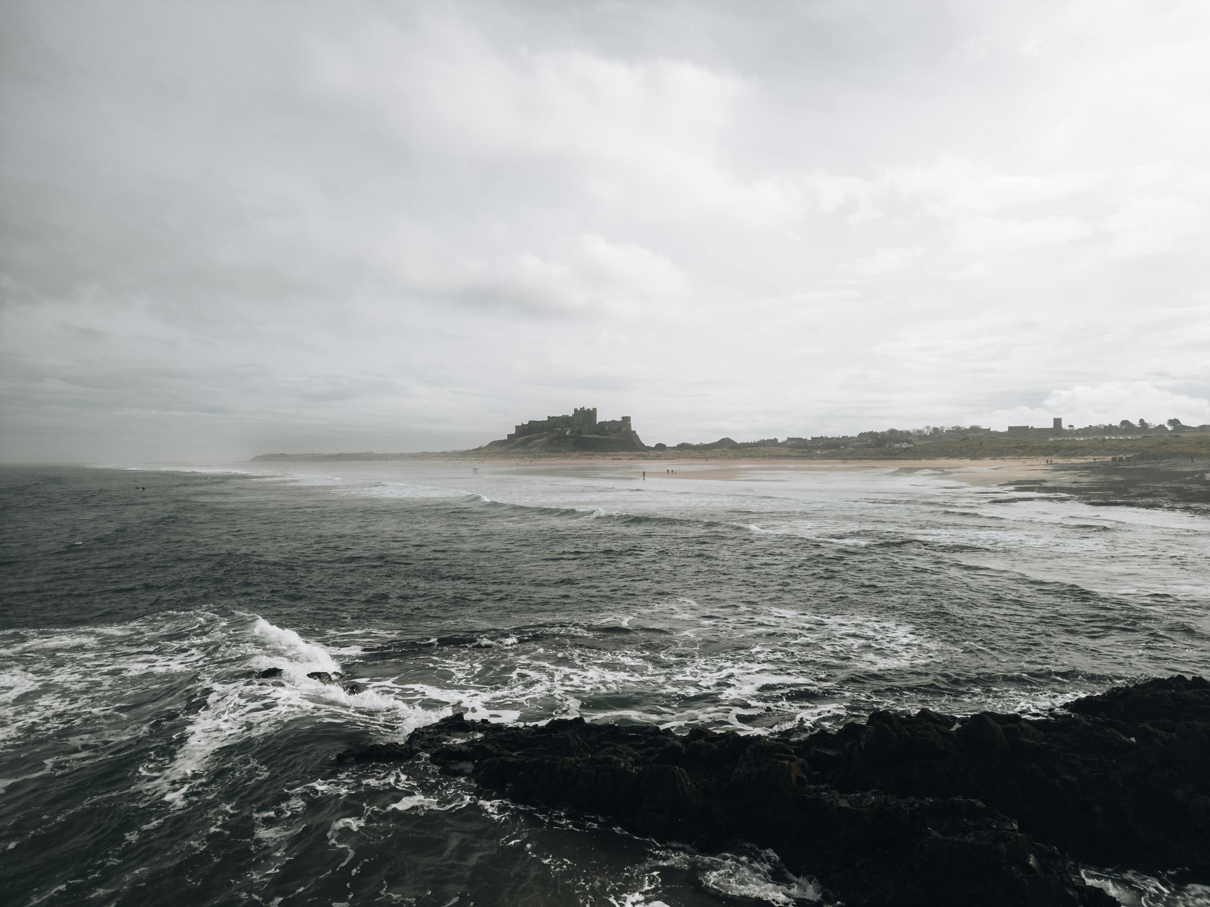 A dramatic scene of Bamburgh Castle overlooking the rugged Northumberland coast in England.