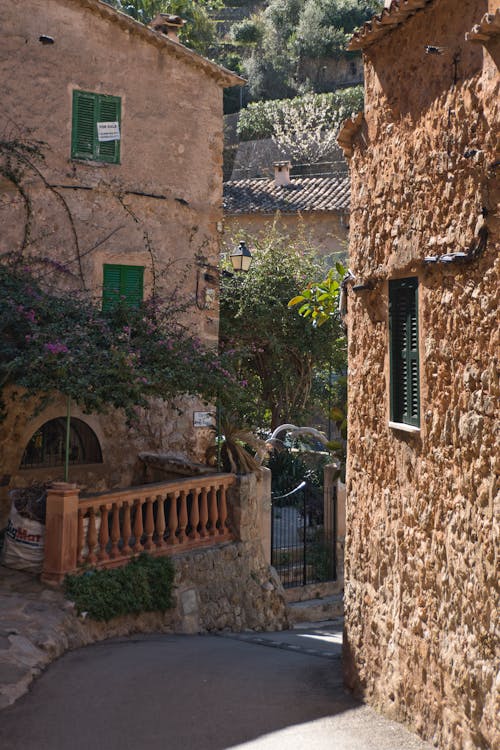 A narrow street with a stone building and green shutters