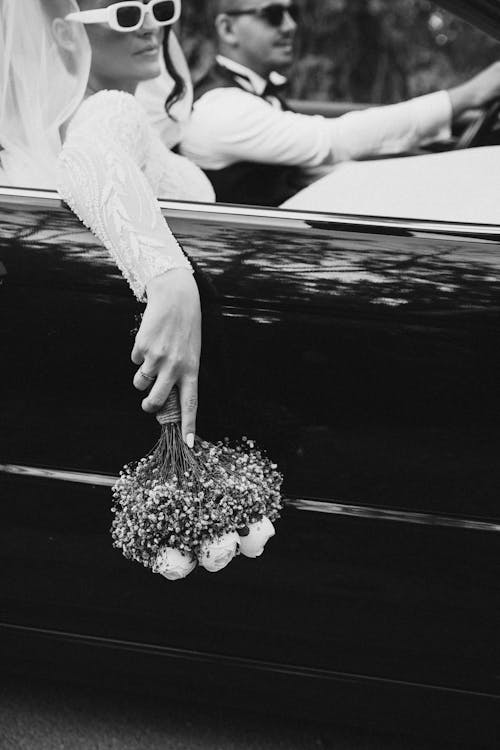 A bride and groom in a car with sunglasses