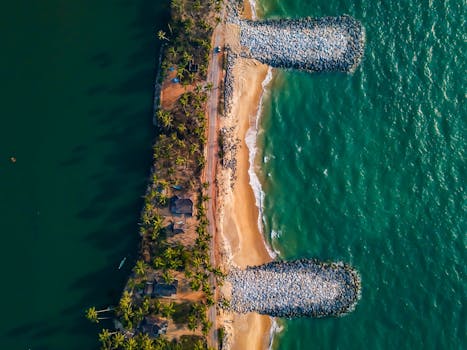 Captivating aerial shot of a beach in Udupi, India, with lush palms and a rocky pier.