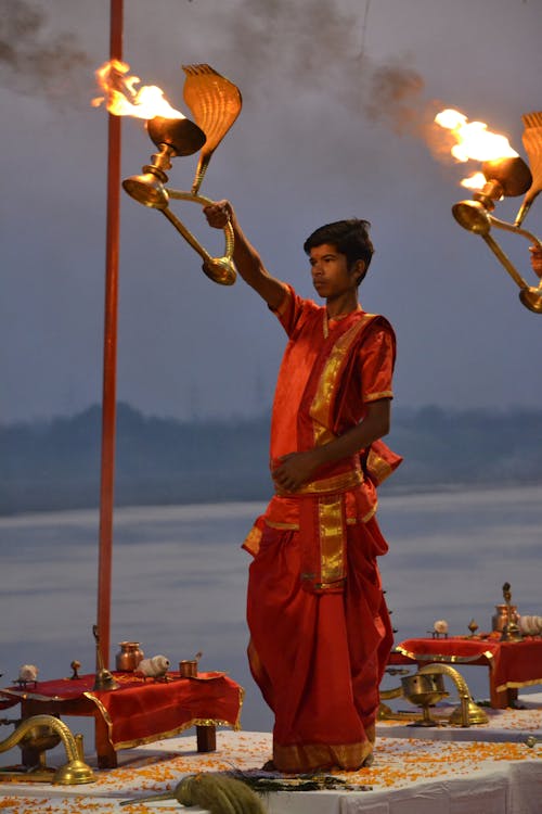 A woman in red holding a torch in front of a river