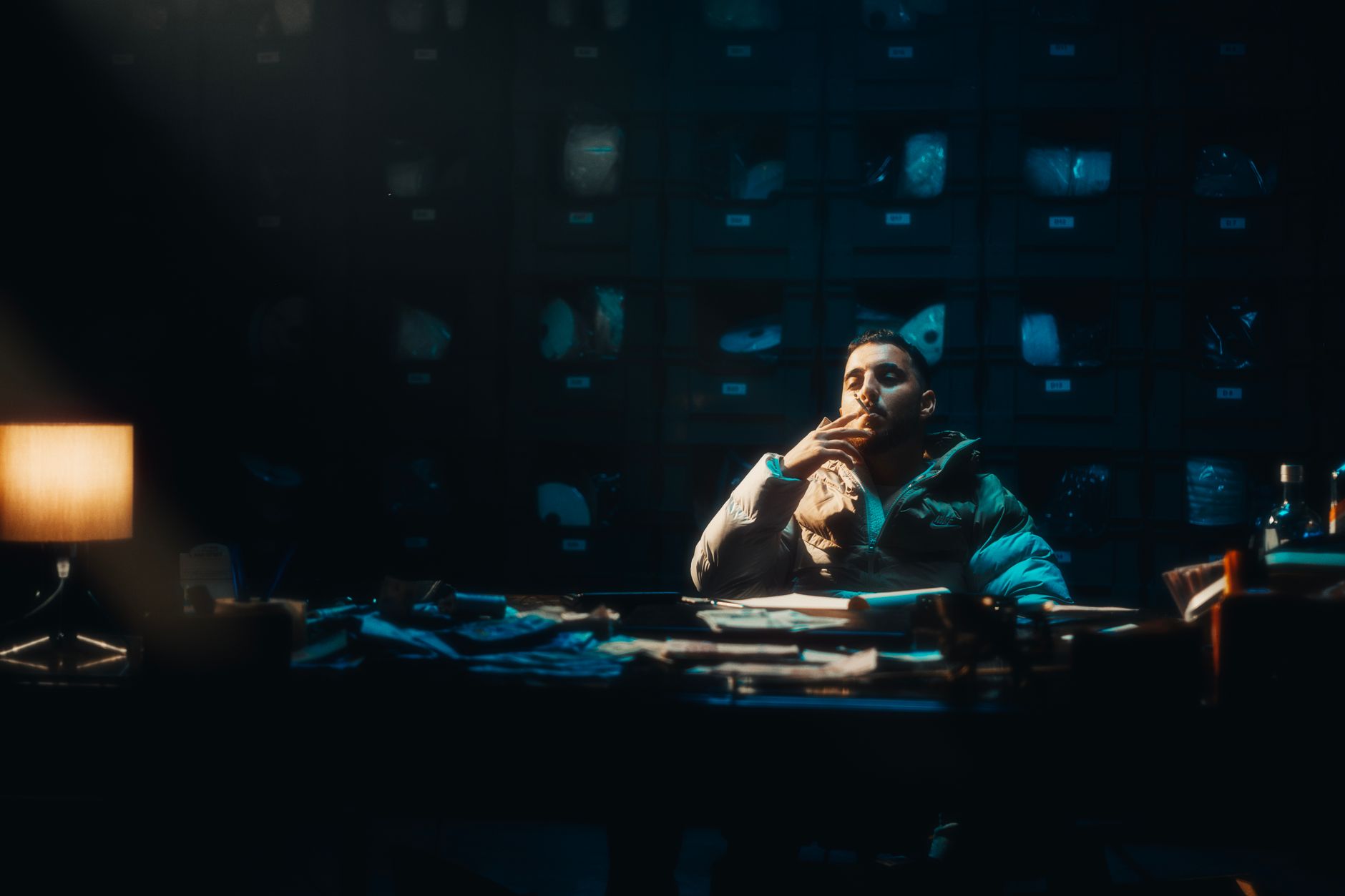 A contemplative man sits smoking in a dimly lit room, adding mystery and ambiance.