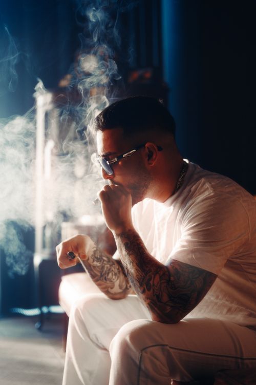 Free A man in sunglasses smoking indoors, exuding a relaxed vibe. Stock Photo