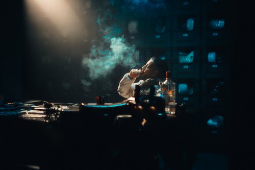 A man smoking in a dark room with a table