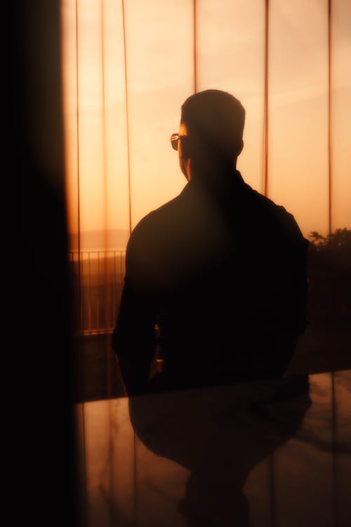 A silhouette of a man looking out a window