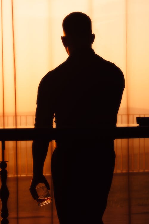 A silhouette of a man standing in front of a window