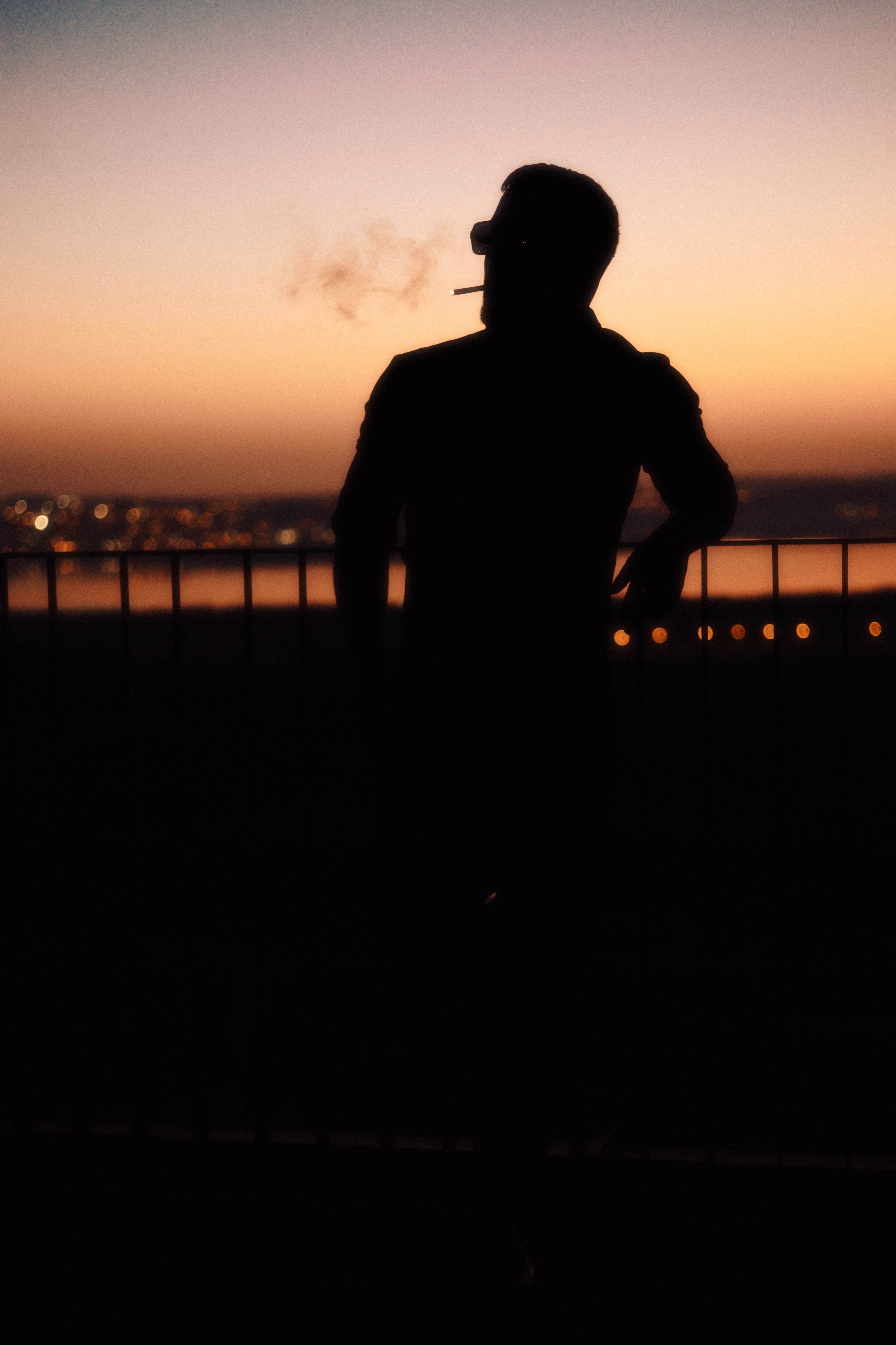 man smoking cigarette silhouette Silhouette of a Man Smoking a Cigarette at Sunset · Free Stock Photo