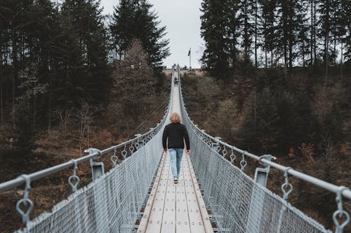 A person walking across a suspension bridge