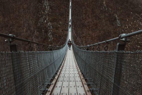 A person walking across a suspension bridge