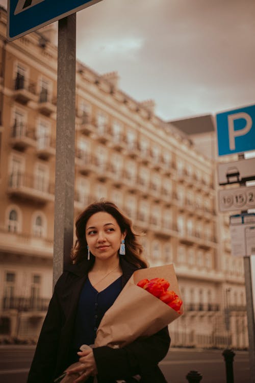 A woman holding a bouquet of flowers in front of a street sign