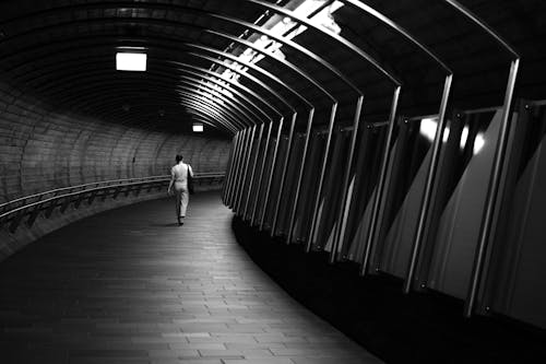 A person walking down a tunnel in black and white