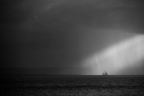 A black and white photo of a sailboat in the ocean