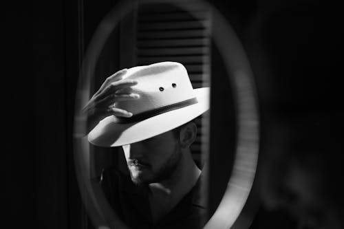 A man in a hat looking in a mirror