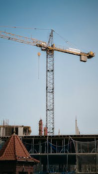 A tall tower crane at a construction site with a clear blue sky in the background.