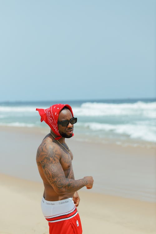 Free A man in red shorts and a red bandana on his head standing on the beach Stock Photo