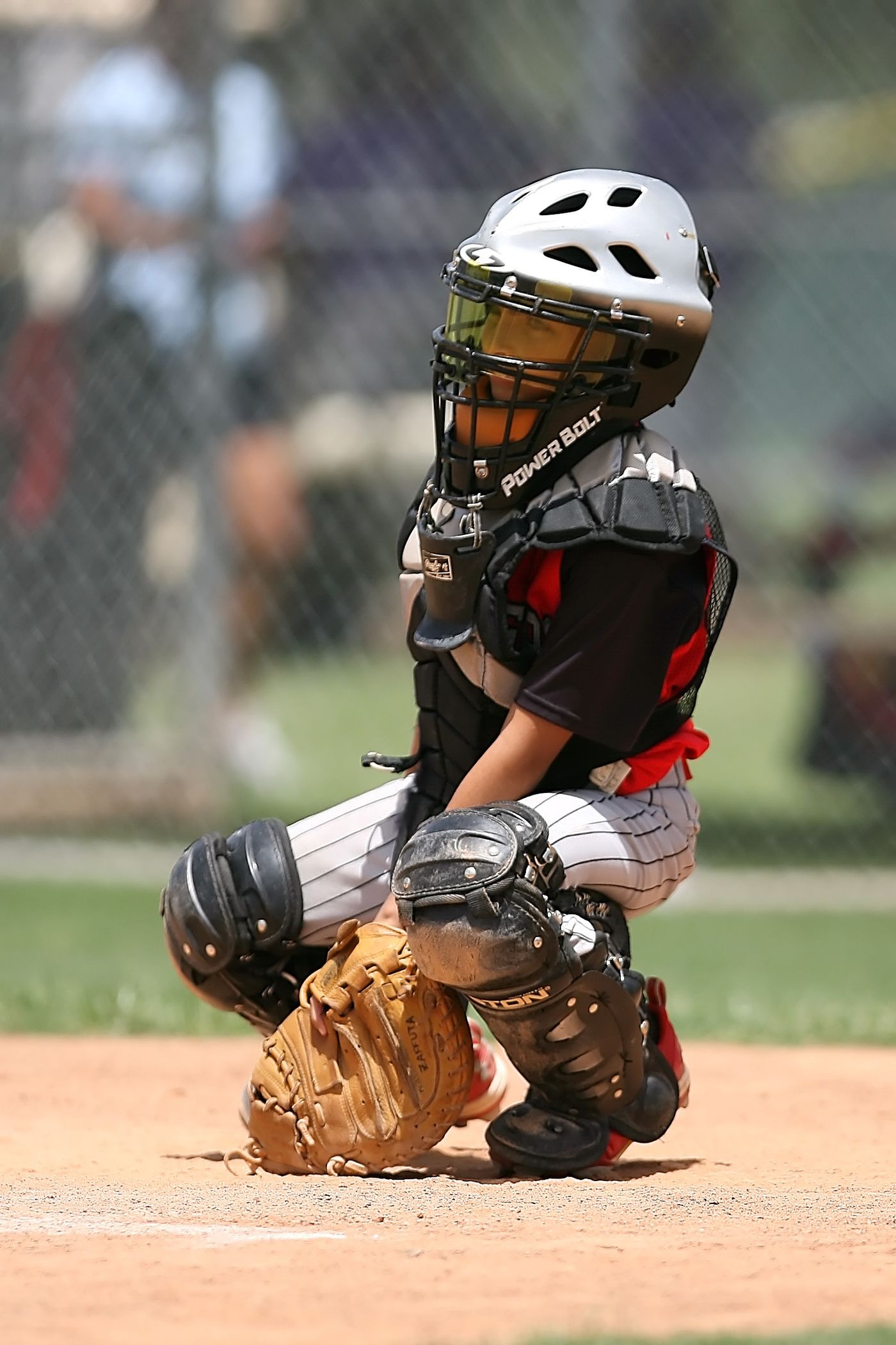 Young catcher crouched behind home plate in full gear
