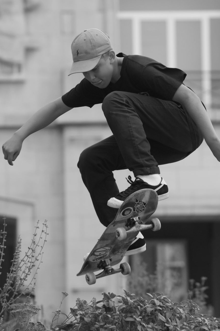 A young male skater in mid-air performing a jump with a skateboard outdoors.. young, male, skater