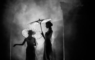 Two figures with parasols in stage mist — photo by Cheng Shi Song on Pexels