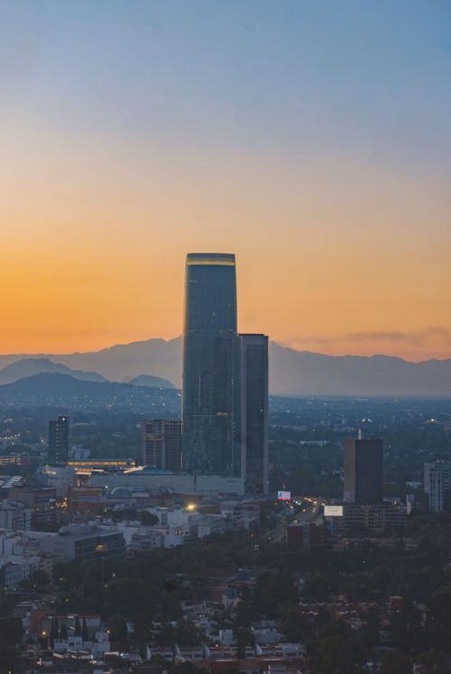 Free View of Ciudad de México's skyline with a prominent skyscraper at sunset. Stock Photo