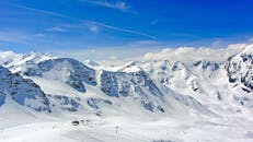 在晴朗的蓝天下，可以欣赏到白雪覆盖的高山壮丽景色，非常适合冬季运动