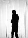 黑白男子的艺术轮廓在窗帘背景下，营造出戏剧性的效果