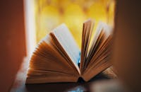 一本打开的书，书页呈扇形展开，背景温暖而模糊