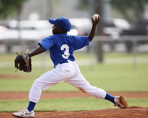 無料 青と白の3ジャージを着た少年が野球を投げようとしている 写真素材