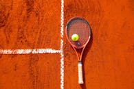 红土球场上的网球拍和球是体育主题内容的理想选择