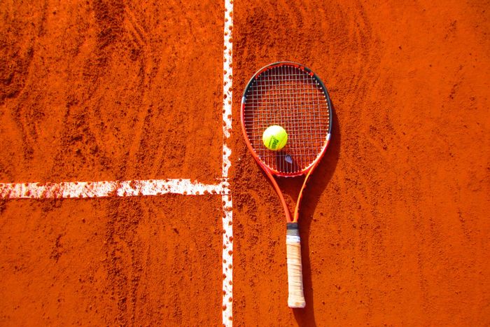 Tennis racket and ball on a clay court