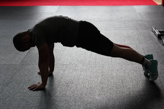 An athlete demonstrates a perfect push-up form in a dimly lit gym setting.