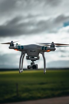 A drone flying over a green field under a dramatic cloudy sky, showcasing technology in nature.