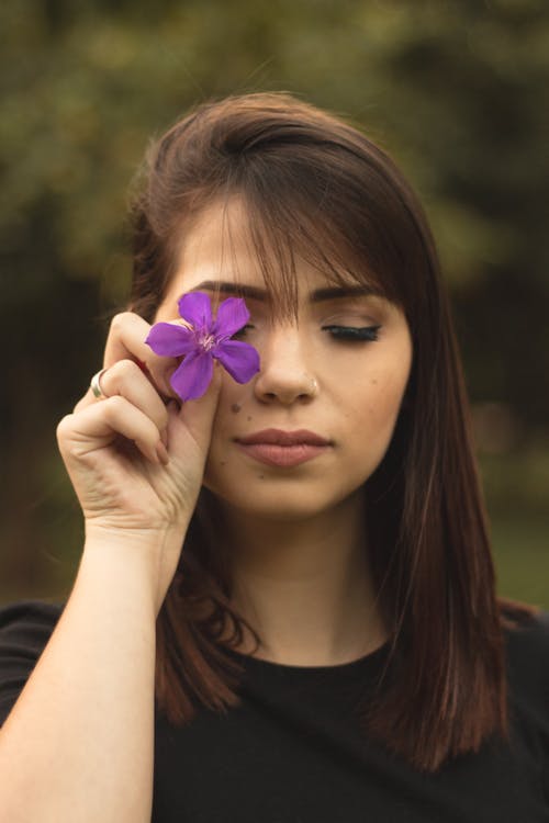 Shallow Focus Photo Of Woman In Black Crew Neck Shirt Holding Purple Flower