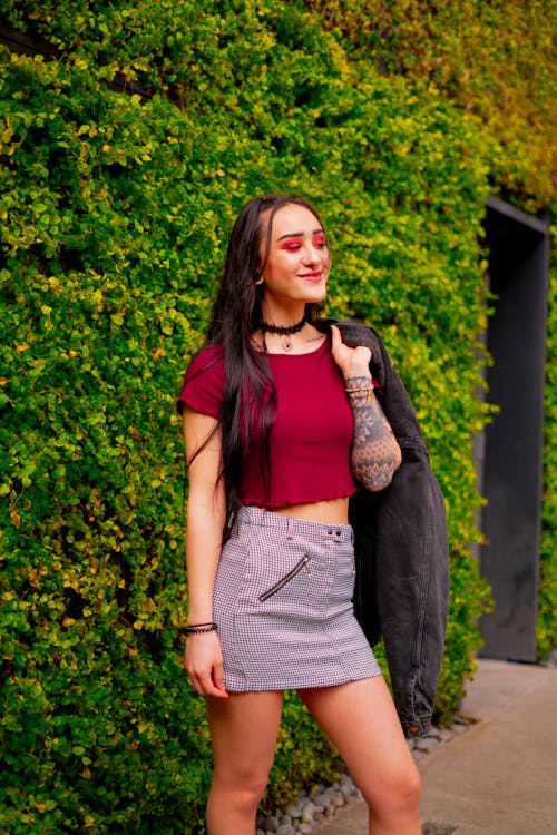 Woman In Red Crop Top And Grey Mini Skirt Holding Black Jacket 