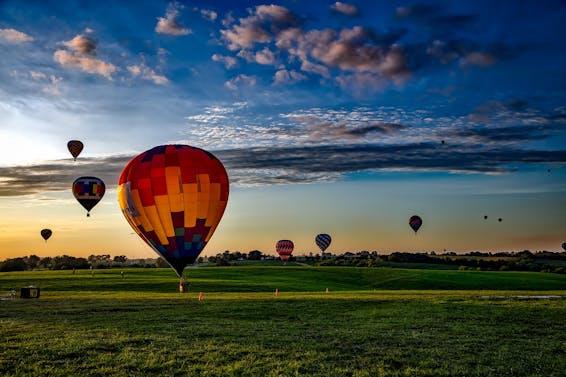 Assorted-color Hot Air Balloons on Grass Field during Golden Hour