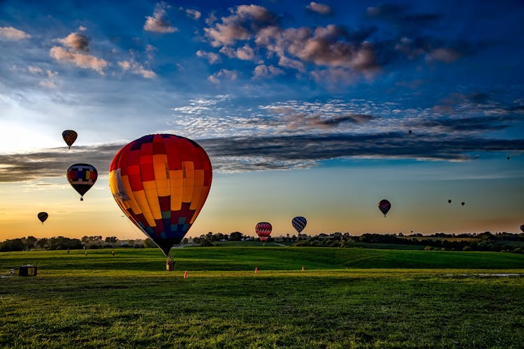 Assorted-color Hot Air Balloons On Grass Field During Golden Hour