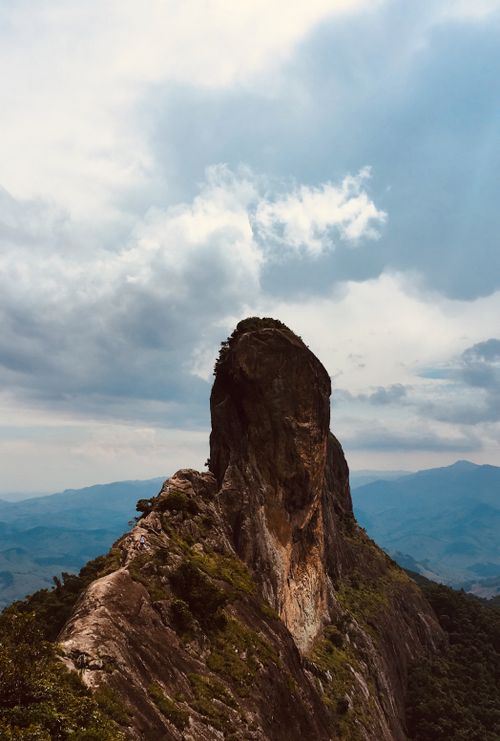 Free Striking mountain peak with dramatic clouds and lush greenery in a natural landscape. Stock Photo