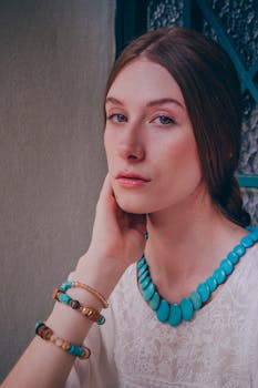 一位时尚女人戴着碧绿色项链和手镯，在室内摆姿势