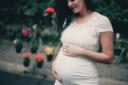 Nahaufnahmefoto Der Schwangeren Frau Im Weißen Kleid, Das Ihren Magen Hält