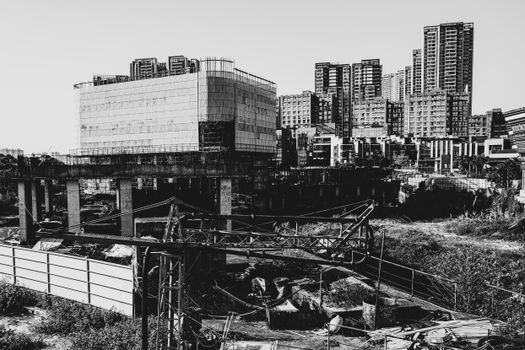 Black and white photo of a construction site with modern buildings in the background.