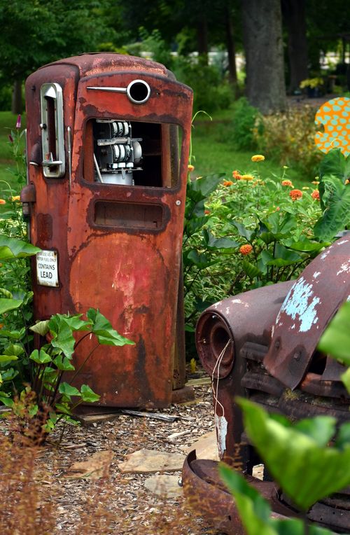 Free An antique gas pump embraced by vibrant foliage and blooms in Knoxville, TN, creating a rustic charm. Stock Photo
